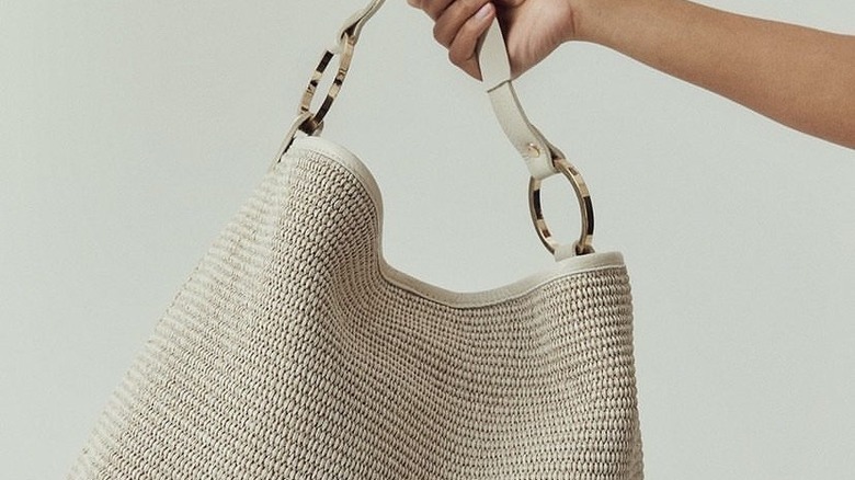 hand holding raffia shoulder bag