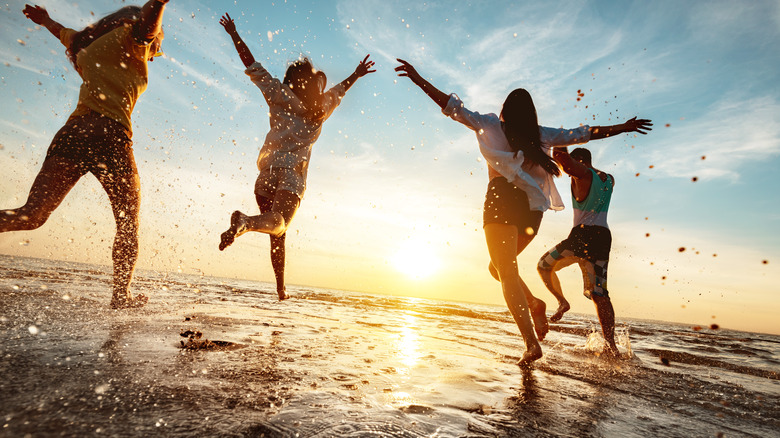 Friends jumping and playing at the beach