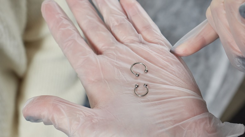 gloved hand showing septum jewelry