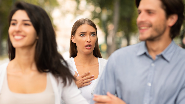 heartbroken girl jealous at a man and a woman laughing happily together