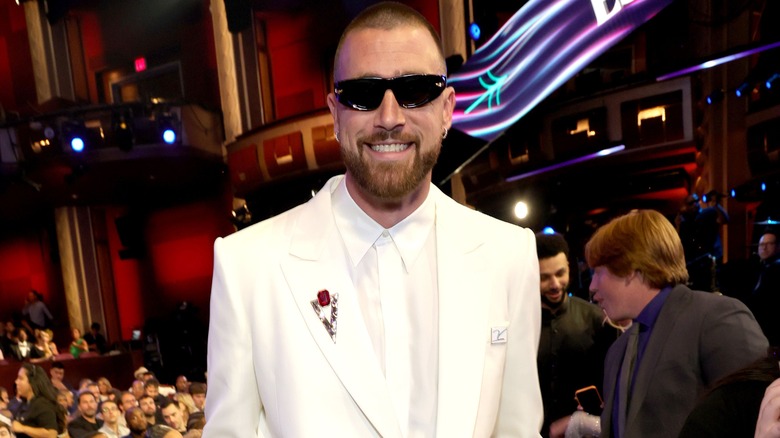 Travis Kelce in a white suit with sunglasses