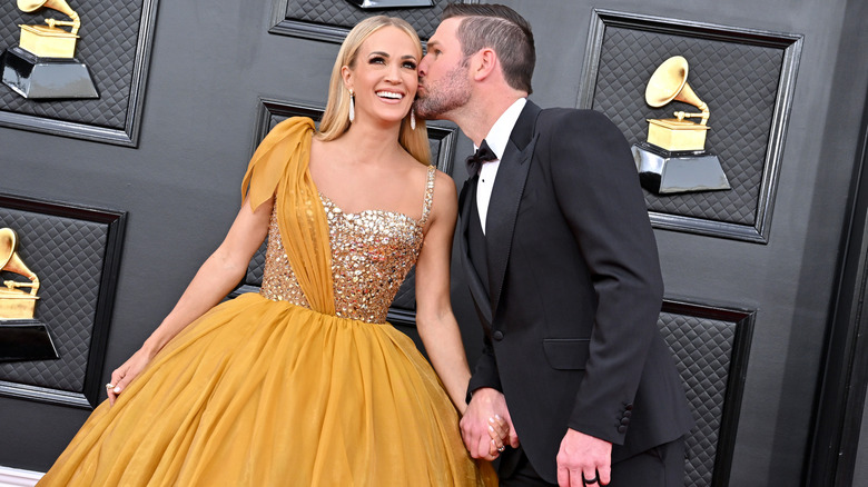 Carrie Underwood and Mike Fisher posing at the Grammy Awards red carpet.