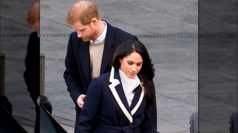 Meghan Markle and Prince Harry stare at the ground.