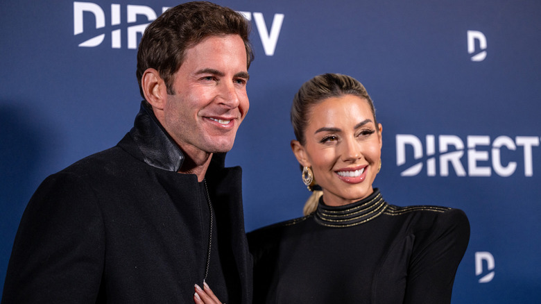 Tarek and Heather Rae El Moussa posing together at a red carpet event.