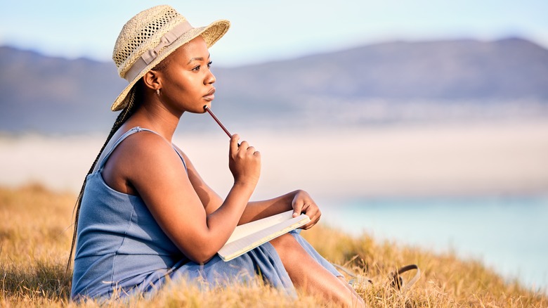 Introspective woman outside holding pen and journal