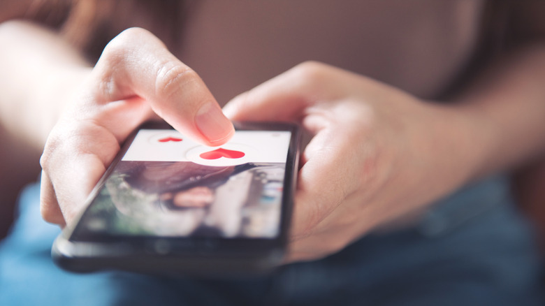 Person sending heart with phone