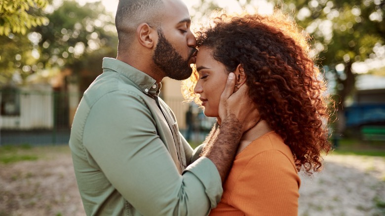 Man kissing woman on forehead