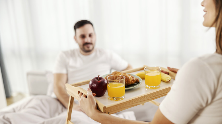 A woman bringing her partner breakfast in bed