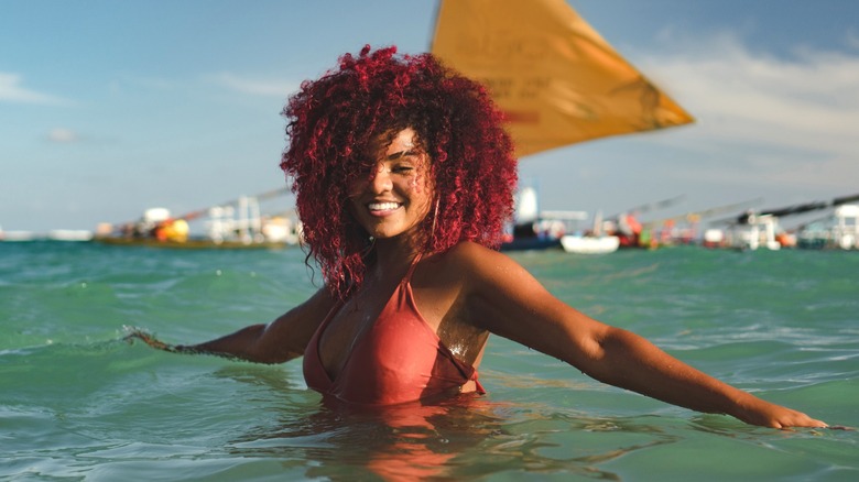 Burgundy hair woman swimming in ocean