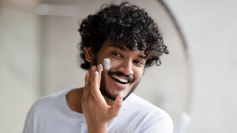 Man applying skincare product to face