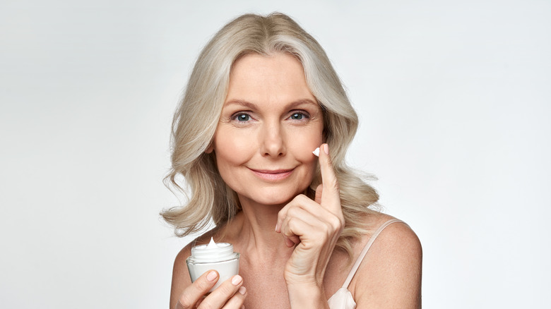 A woman applying face cream 