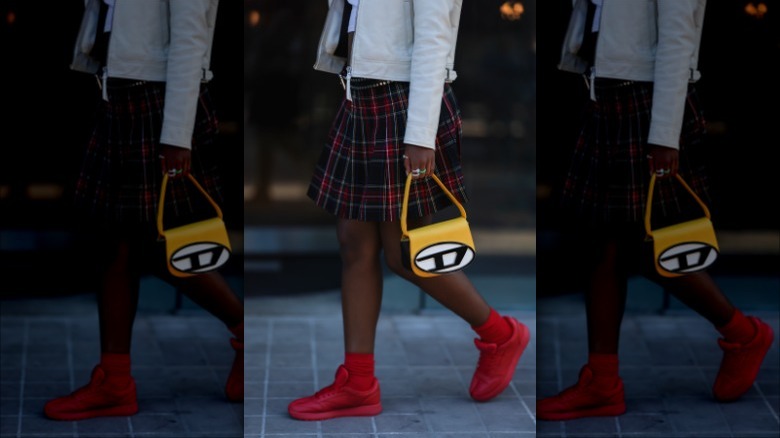 Woman wearing skirt, red sneakers