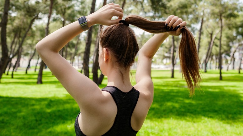 woman putting her hair into ponytail