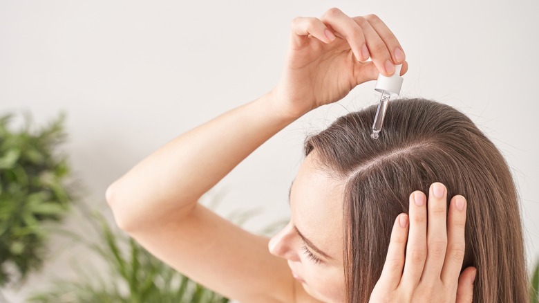 woman applying serum to scalp