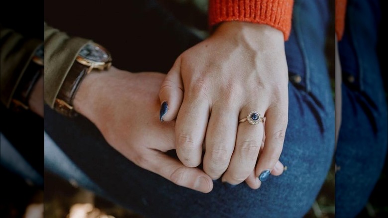 Hand displaying round sapphire engagement ring 