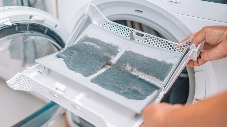 man takes lint filter out of tumble dryer 