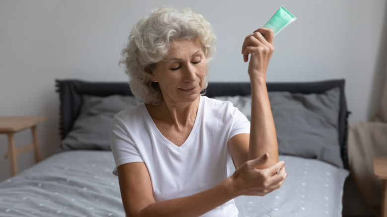 Woman applying lotion to elbows