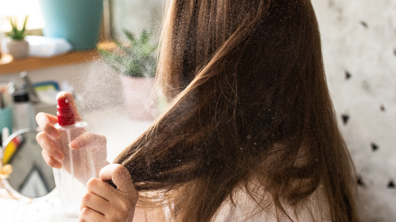woman spraying product on her hair 