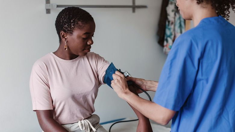 Doctor testing woman's blood pressure