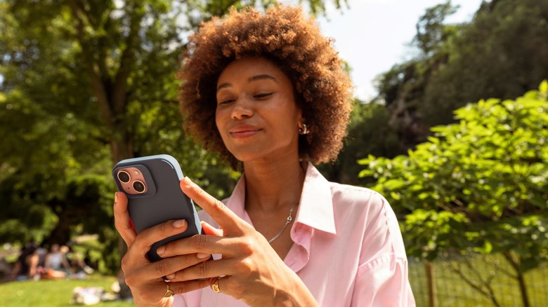 Woman in a park smiling at her phone