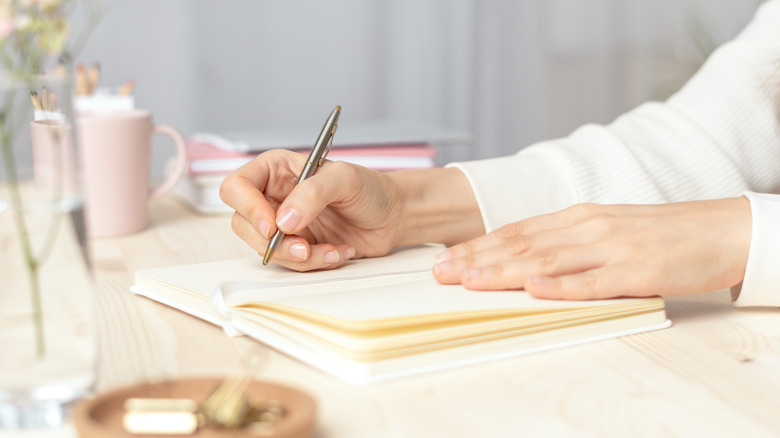 Woman's hands writing in journal