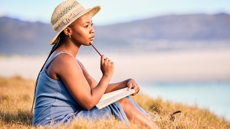 Thoughtful woman writing in journal outside