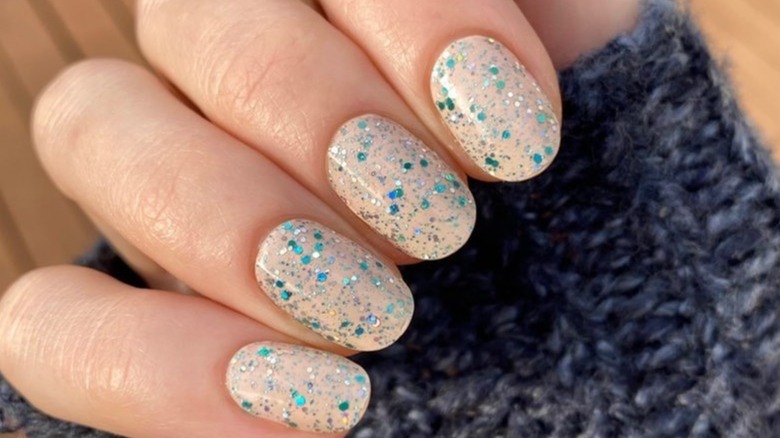 nude nails with blue confetti on top