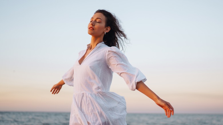 Woman closing eyes by ocean