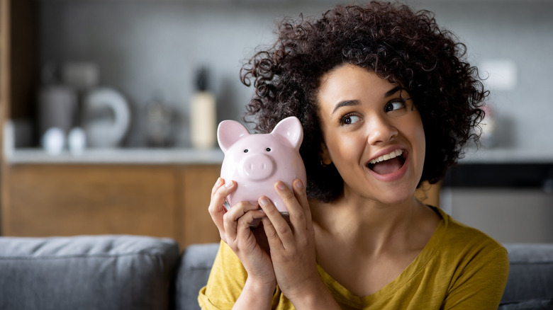 Woman celebrates money in piggy bank