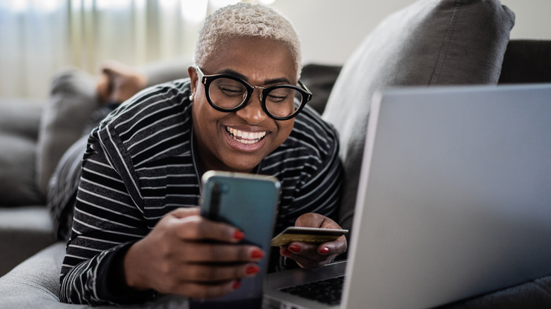 Woman shops online using cell phone and laptop