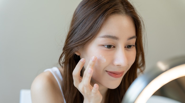 woman applying makeup in mirror