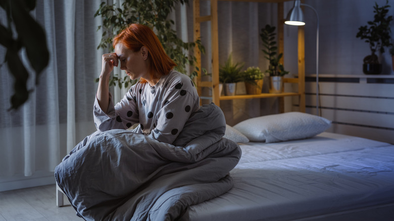 Stressed woman sitting on bed alone