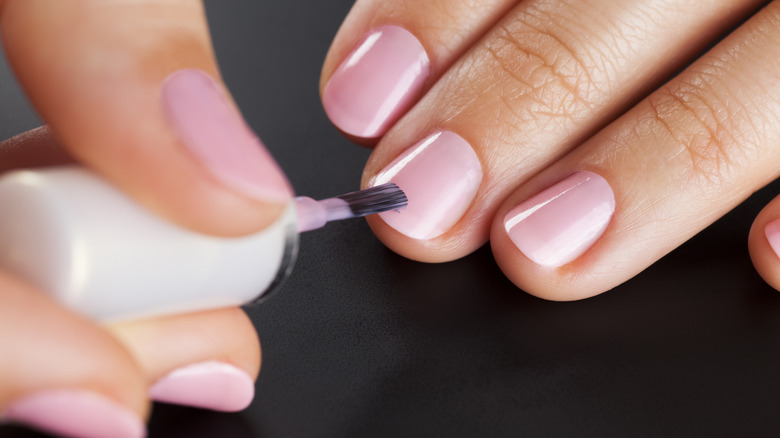 Person applying light pink nail polish