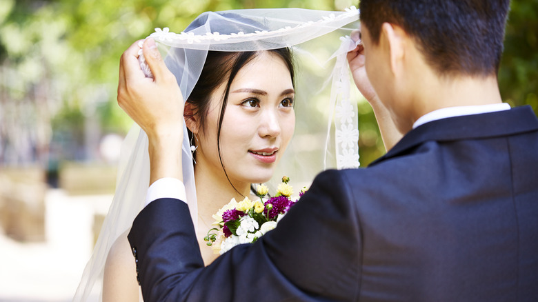 groom lifting the veil to kiss bride