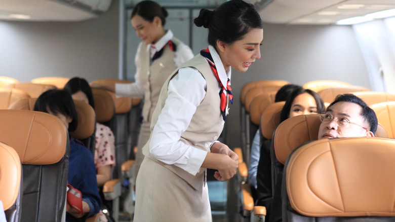 air hostess in airplane speaking passenger