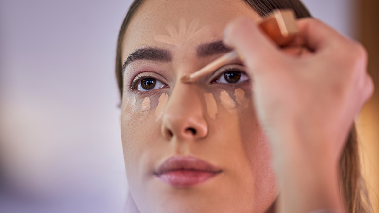 person applying concealer on woman