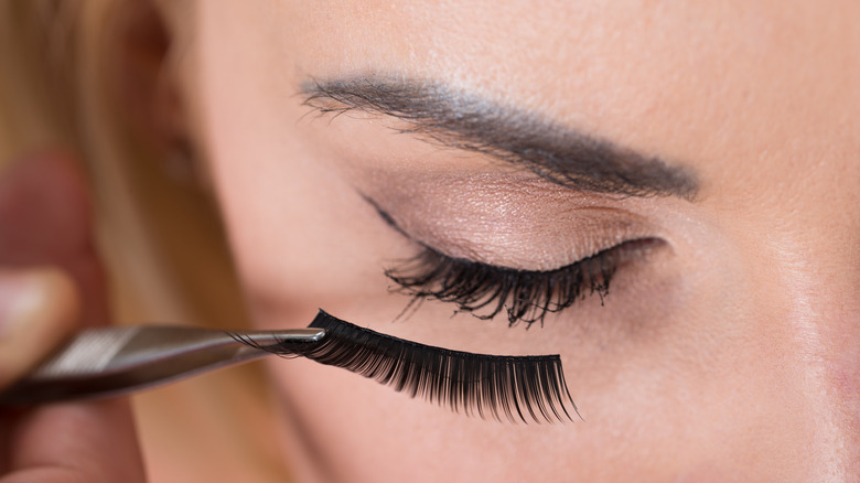 applying false lashes to lashes with mascara