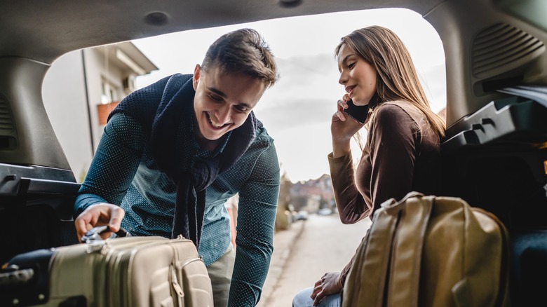 couple packing luggage in car