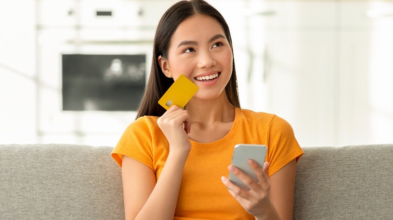 woman holding credit card and phone