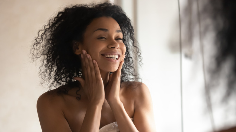 woman with beautiful skin smiling at mirror