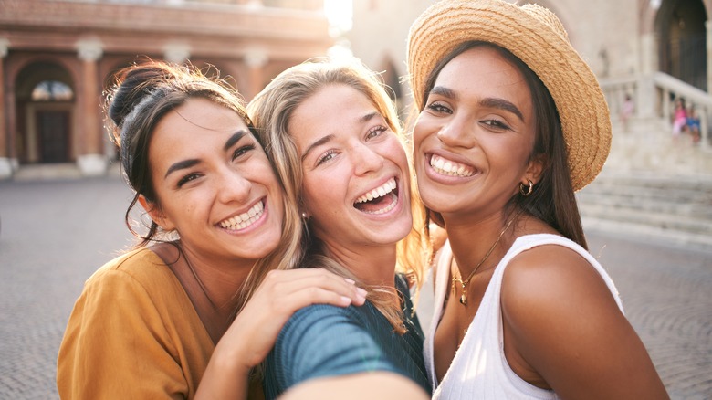 three smiling women during travels