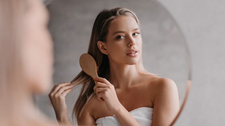 woman brushing hair in mirror