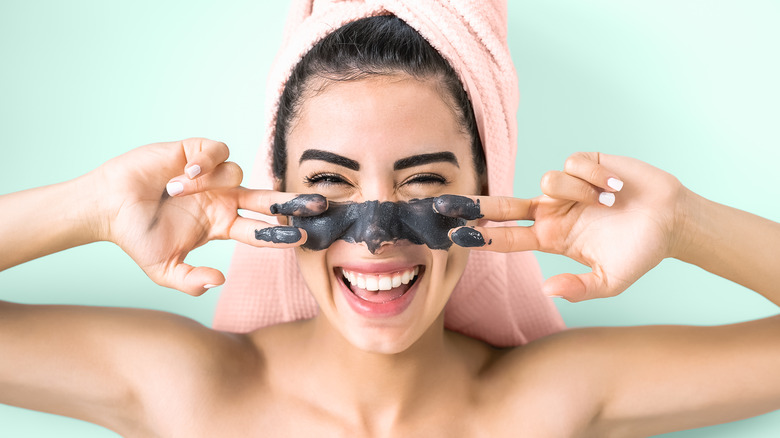 young woman putting on clay face mask