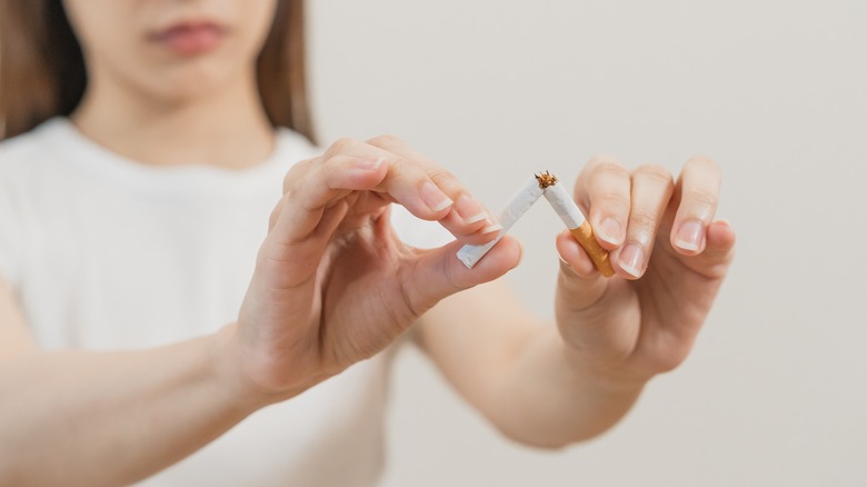 woman breaking cigarette in half