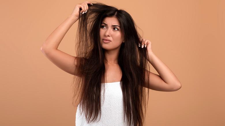 frustrated woman holding damaged hair