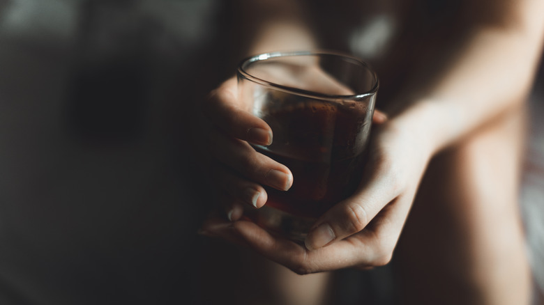 hands holding glass of whiskey