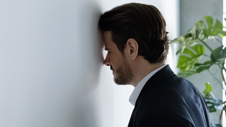 man with head against wall