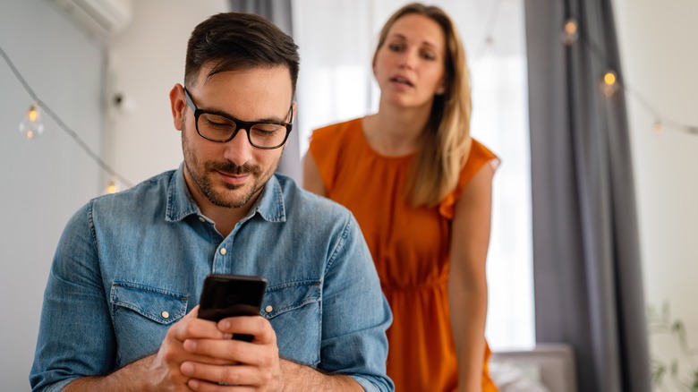 woman looking at texting man