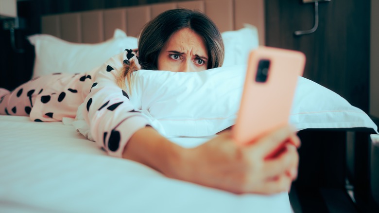 woman in bed looking at phone