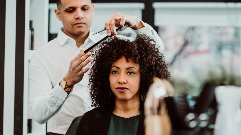 curly haired woman getting hair cut